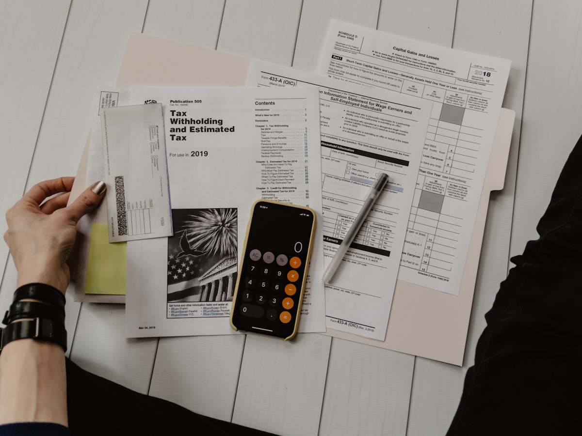 Déclarations fiscales, calculatrice et stylo posés sur un bureau